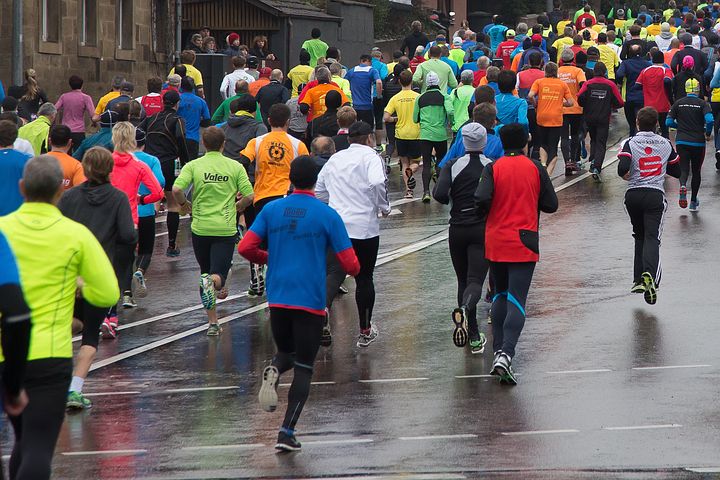 large group of runners taking part in a marathon on a rainy day